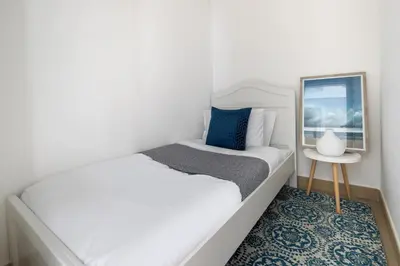 a white bedroom with a bed and a side table at Frank Porter - Burj Vista 1 in Dubai