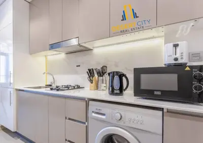 a kitchen with a washing machine and a microwave at Azizi Riviera 7 - Meydan City, Dubai in Dubai