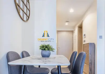 a dining room with a white table and blue chairs at Azizi Riviera 7 - Meydan City, Dubai in Dubai
