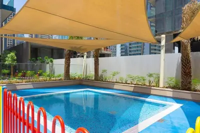 a swimming pool with an umbrella and chairs at 1BDR in Marina Gate Skylineview in Dubai