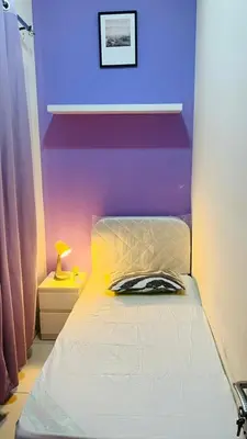 a bed in a room with a purple wall at Peaceful Partition Room Near Mall of the Emirates in Dubai