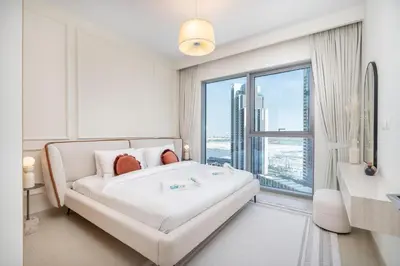a white bedroom with a bed and a large window at Elegant apartment in Dubai Creek Harbour in Dubai