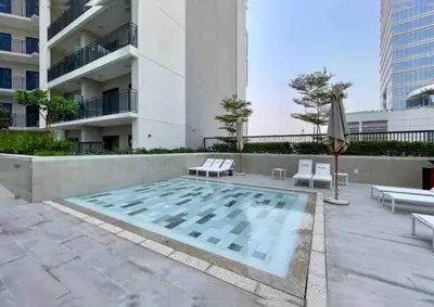 a swimming pool with benches and an umbrella in front of a building at Near Burj Khalifa NYE Brand New Cozy 1BR Business Bay in Dubai