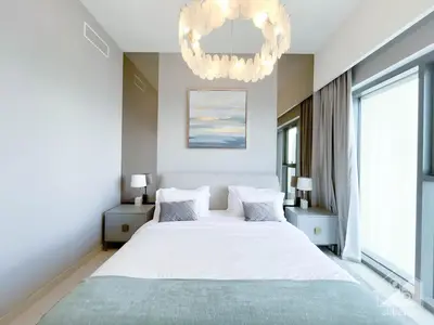 a bedroom with a large white bed and a chandelier at Luxury Burj Royale Apt balcony & Breathtaking View in Dubai