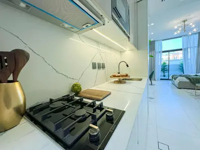 a kitchen with a stove top oven in a kitchen at Bright New Studio with Pool & Gym Access, 5 min from Gardens Metro in Dubai