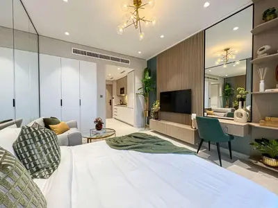 a bedroom with a large white bed and a living room at Bright New Studio with Pool & Gym Access, 5 min from Gardens Metro in Dubai