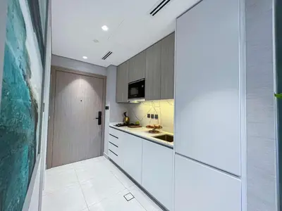 a kitchen with white cabinets and a sink at Bright New Studio with Pool & Gym Access, 5 min from Gardens Metro in Dubai