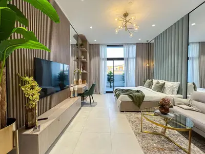 a living room with a bed and a tv at Bright New Studio with Pool & Gym Access, 5 min from Gardens Metro in Dubai