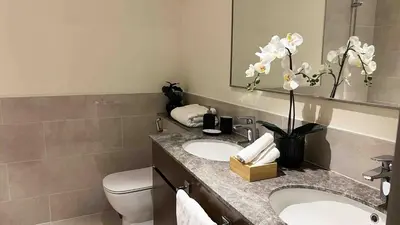 a bathroom with two sinks and a toilet and a mirror at Brand new 2 BR in Boulevard with partial Burj Khalifa and Opera View in Dubai
