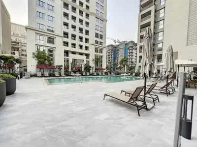a swimming pool with chairs and umbrellas in a building at Summer at Creek Beach - Elegant One Bedroom in Dubai