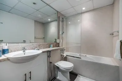 a bathroom with a sink and a toilet and a mirror at Serene & Spacious 1BR The Greens in Dubai
