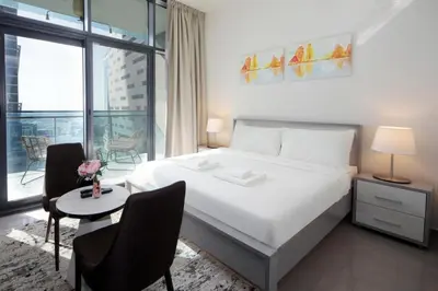 a bedroom with a white bed and a table and chairs at Studio Apartment in Merano Tower by The S Holiday Homes in Dubai