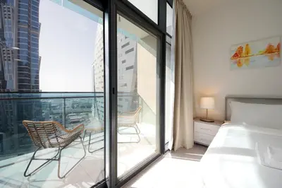 a bedroom with a balcony with a bed and a table at Studio Apartment in Merano Tower by The S Holiday Homes in Dubai