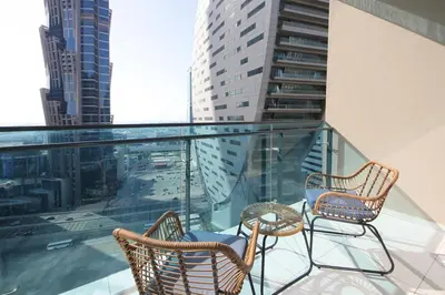 two chairs and a table on a balcony with buildings at Studio Apartment in Merano Tower by The S Holiday Homes in Dubai