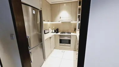 a small kitchen with white cabinets and a refrigerator at Address Fountain View Tower 2 in Dubai