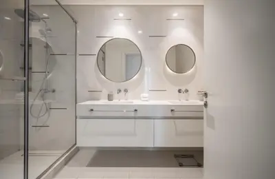 a white bathroom with a sink and two mirrors at Palm View - Beach Vista T1 in Dubai