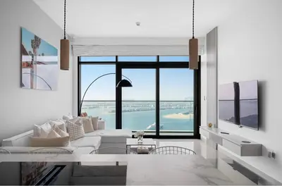 a living room with a white couch and a large window at Palm View - Beach Vista T1 in Dubai