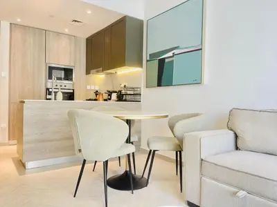 a kitchen and living room with a table and chairs at Brand New Luxury 1 Bedroom Apartment in Dubai