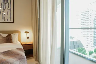 a bedroom with a bed and a large window at Beachfront Bliss - Apartment with Pool and Premium Amenities By ĀYA Boutique in Dubai