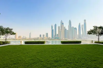 a green park with a city skyline in the background at Beachfront Bliss - Apartment with Pool and Premium Amenities By ĀYA Boutique in Dubai