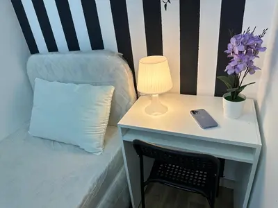 a bed with a table with a lamp and a pillow at Lovely Private Partition Room in Barsha Heights in Dubai