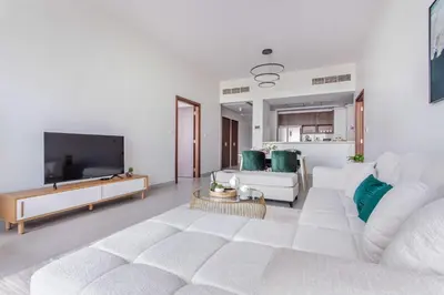 a living room with a white couch and a tv at Frank Porter - Park Gate Residences 1 in Dubai
