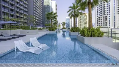 a swimming pool with two white chairs and palm trees at Burj Khalifa Views! Promo on 1BR at Sterling House by Deluxe Holiday Homes in Dubai