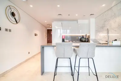 a kitchen with two bar stools at a counter at Burj Khalifa Views! Promo on 1BR at Sterling House by Deluxe Holiday Homes in Dubai
