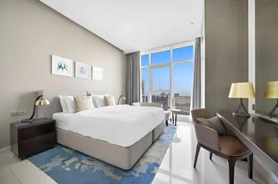 a bedroom with a bed and a desk and a large window at ALiving Charming 1BR I Canal Views I DAMAC Maison Prive B- 2101 in Dubai