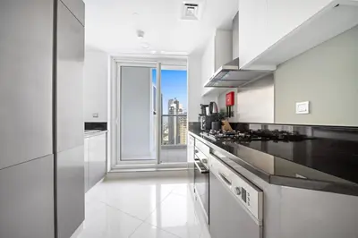 a white kitchen with a view of the city at ALiving Charming 1BR I Canal Views I DAMAC Maison Prive B- 2101 in Dubai