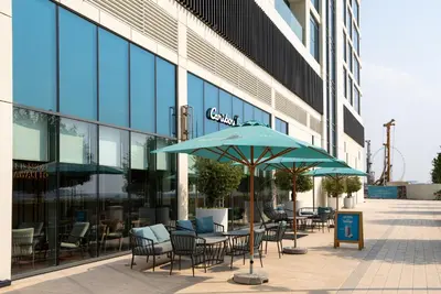 a table and chairs with an umbrella in front of a building at Fully Furnished - 1 BR - Palm View with Beach Access in Dubai