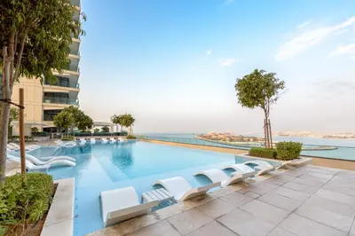 a large swimming pool with white lounge chairs at Fully Furnished - 1 BR - Palm View with Beach Access in Dubai
