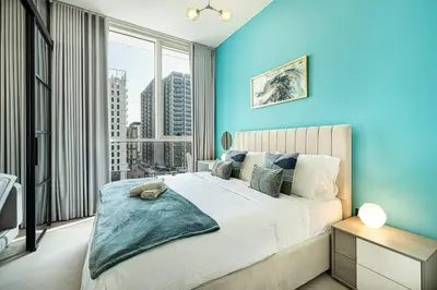 a blue bedroom with a bed and a large window at Beautiful 1 Bedroom Dubai Hills with Pool View in Dubai