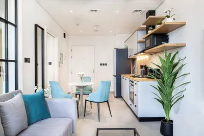 a kitchen and a living room with a couch and a table at Beautiful 1 Bedroom Dubai Hills with Pool View in Dubai