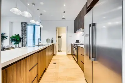 a kitchen with wooden cabinets and a stainless steel refrigerator at Sea View 3 BD apartment in La Mer near the beach in Dubai