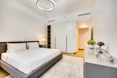 a white bedroom with a bed and a table at Sea View 3 BD apartment in La Mer near the beach in Dubai