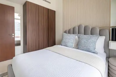 a bedroom with a large bed with white sheets and blue pillows at Frank Porter - Reva Residence in Dubai