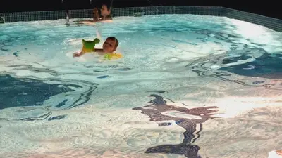 two children are swimming in a swimming pool at Marina View Manchester tower in Dubai