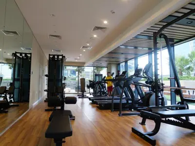 a gym with many treadmills and people in the background at Quiet 1BR with river view in Dubai