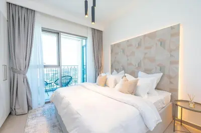 a white bedroom with a large bed and a balcony at The Legend Fashionable 2 Bed Apartment in Downtown in Dubai