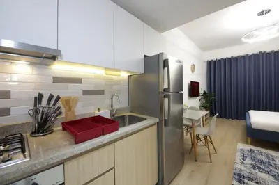 a kitchen with a stainless steel refrigerator and a table at Aura Azizi - Downtown Jabel Ali by Golden Casa in Dubai