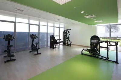 a gym with treadmills and machines in a room at Aura Azizi - Downtown Jabel Ali by Golden Casa in Dubai