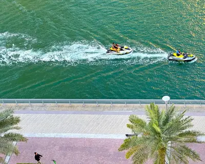 two people on boats in the water near a beach at Unforgettable Canal & Sea View in Dubai Marina in Dubai