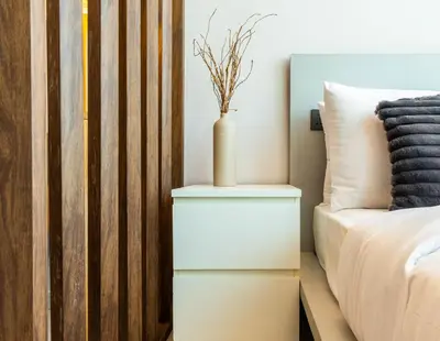 a white nightstand next to a bed with a vase on it at Unforgettable Canal & Sea View in Dubai Marina in Dubai