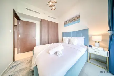 a bedroom with a large white bed with a blue headboard at Hot Offer Modern 1BR with Scenic Water Canal Views by Deluxe Holiday Homes in Dubai