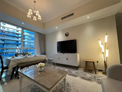 a living room with a television and a table at 3 Minutes to Dubai Mall! DVR Vacation Homes in Dubai