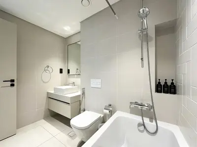 a white bathroom with a toilet and a sink at Trophy - Marina Vista Sea View Suite in Dubai