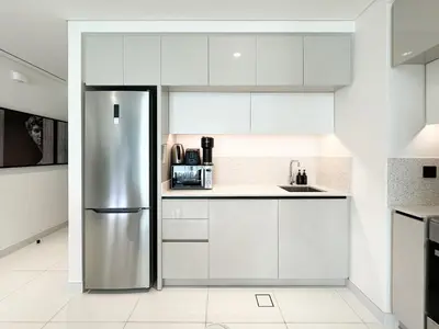 a kitchen with white cabinets and a stainless steel refrigerator at Trophy - Marina Vista Sea View Suite in Dubai