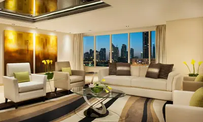 a living room with white furniture and a view of the city at DAMAC Maison Canal Views in Dubai