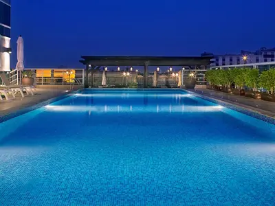 a large blue swimming pool at night at Armada Avenue Hotel in Dubai